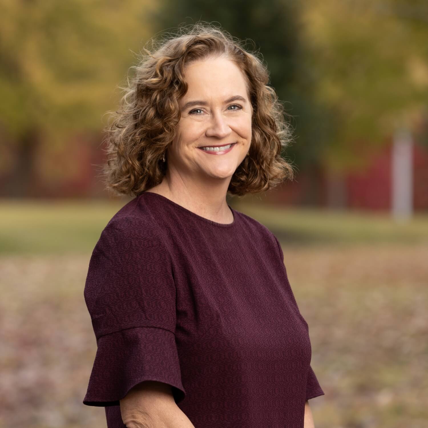 Angela Duran, Executive Director of Excel by Eight, smiling outdoors in professional attire.