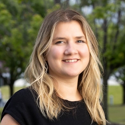 Outdoor headshot of Tori Scott, smiling in front of trees, serving as the contact for Excel by Eight Communities.